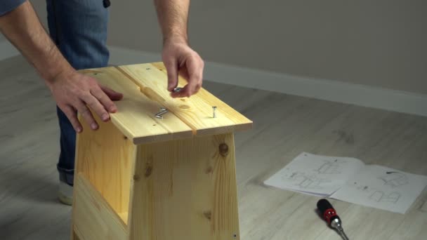 Manos de hombre montando muebles de madera. Hombre armando tablones con tornillo y llave allen — Vídeos de Stock