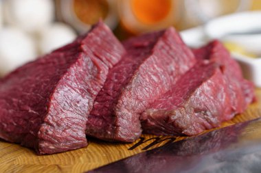 Bıçağın yanında ızgara biftekler, kesme tahtasındaki baharatlar için çiğ et hazır. Sağlıklı gıda konsepti