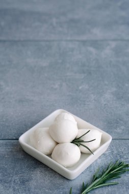 Taze İtalyan beyaz peyniri mozzarella bufalosu beyaz kâse içinde taze biberiye dalıyla servis edilir.