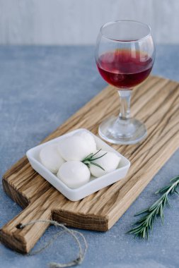 Beyaz kasede yumuşak İtalyan beyaz peyniri mozzarella taze biberiye dalı ve şarap kadehiyle servis edilir.