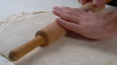 Erkek ellerine yakın çekim, lezzetli geleneksel pizzalar yapıyor. Şef hamuru oklavayla yuvarlıyor.