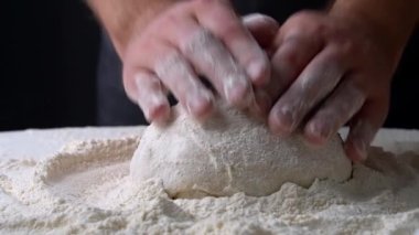 Şef hamur hamuruna un serpiyor. Hamur ahşap masada yatıyor. Görüntüyü kapat