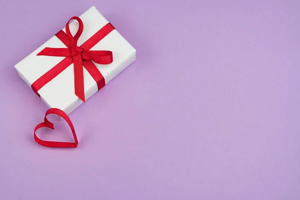 День Святого Валентина или день рождения с копировальным пространством. Красная лента сердце и подарочная коробка на фиолетовый papper — стоковое фото