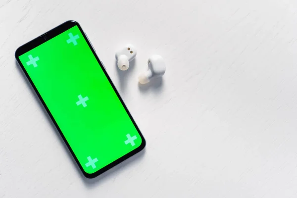 Smartphone med gren skärm mockup och vita trådlösa hörlurar isolerade på vit bakgrund — Stockfoto