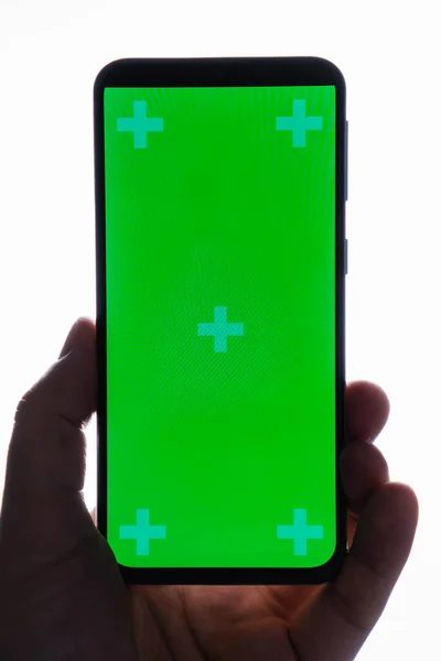 Κοντινό πλάνο του χεριού κρατώντας σύγχρονο smartphone με πράσινη οθόνη αφής που απομονώνονται σε λευκό φόντο — Φωτογραφία Αρχείου