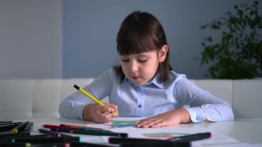 Çocukların yaratıcılığı. Evinde renkli kalemlerle gökkuşağı çizen küçük bir kız çocuğu.