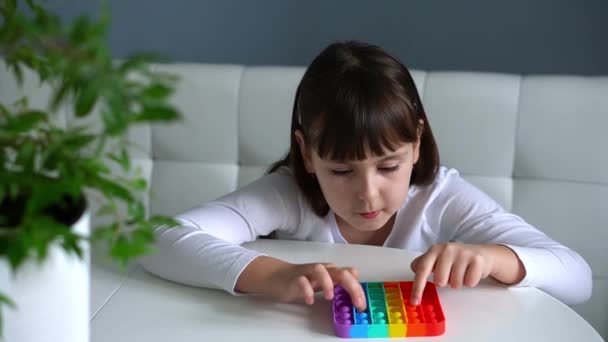 Κοριτσάκι παίζει με ουράνιο τόξο pop αυτό fidget. Η έννοια της ψυχικής υγείας popit παιχνίδι — Αρχείο Βίντεο