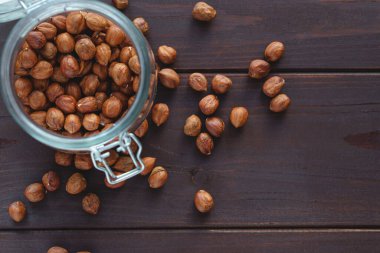 Kahverengi fındığı cam kavanoza ve ahşap masaya koy. Sağlıklı organik vejetaryen fındık