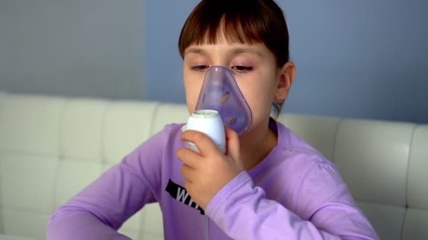 Dívka dělá inhalaci s lékařským nebulizátorem, zatímco sedí u stolu — Stock video