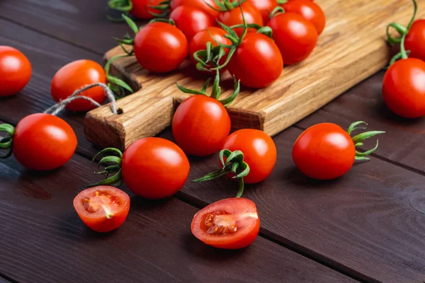 Ahşap masada tahta kesme tahtasındaki cam kasede kırmızı domates. Organik sağlıklı yiyecekler. Mutfak malzemeleri. Pomodoro masada.