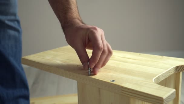 Assemblage de meubles bricolage. Artisan entraîne vis dans le panneau en bois avec tournevis électrique — Video