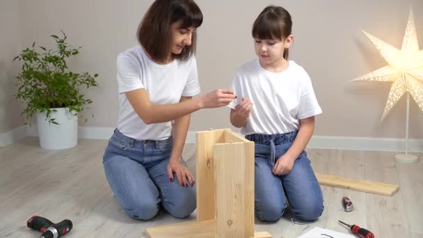 O familie fericită, mamă și fiică, asamblând mobilier din lemn împreună. Conceptul DIY — Videoclip de stoc