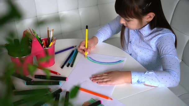 Criatividade infantil. Criança menina desenho arco-íris com lápis coloridos em papel em casa — Vídeo de Stock