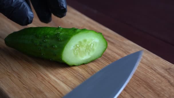 Skär en japansk gurka med kniv på en träskärbräda. Ingrediens för sallad. Närbild — Stockvideo