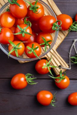 Ahşap masada tahta kesme tahtasındaki cam kasede kırmızı domates. Organik sağlıklı yiyecekler. Yemek İçindekiler