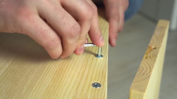 Primer plano manos montaje de muebles de madera. Hombre armando tablones con tornillo y llave allen — Vídeos de Stock