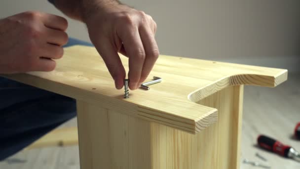 Руки крупным планом собирают деревянную мебель. Человек, соединяющий доски с винтом и ключом — стоковое видео