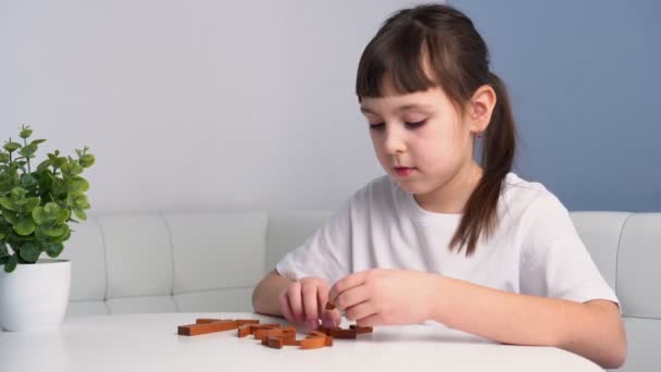 Мила дитина збирає дерев'яні геометричні головоломки. Маленька дівчинка грає з іграшкою. Концепція освітніх ігор — стокове відео