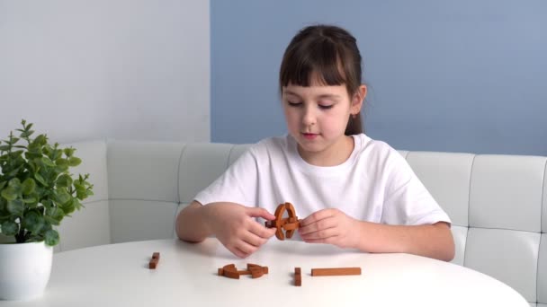 Χαριτωμένο παιδί συλλέγει ξύλινα γεωμετρικά παζλ. Το κοριτσάκι παίζει με το παιχνίδι. Έννοια εκπαιδευτικών παιχνιδιών — Αρχείο Βίντεο