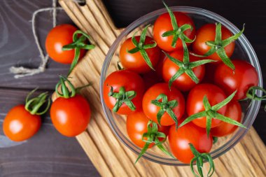 Ahşap masada tahta kesme tahtasındaki cam kasede kırmızı domates. Organik sağlıklı yiyecekler. Yemek İçindekiler