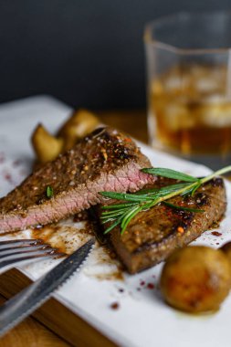 Taze ızgara et. Biberiyeli brunch ve ahşap kesim tahtasında mantarlı orta pişmiş biftek.