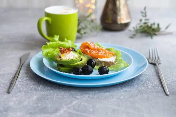 Sağlıklı kahvaltı. Füme somonlu sandviç, marul salatası yapraklı avokado peyniri ve kahve.