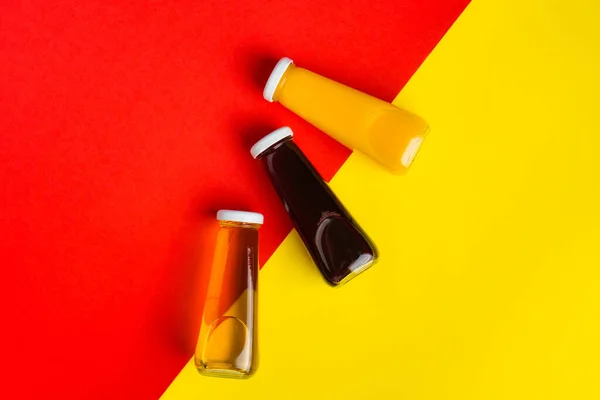 Lahvičky se žlutou a červenou tekutinou halthy nápoj na žlutém a červeném pozadí. Oranžová třešeň Stock Fotografie