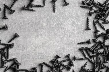 Donanım yapıyorum. Beton gri arka planda kendi kendine dokunan siyah vidalar. Uzayı kopyala Üst görünüm