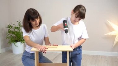 Mutlu aile annesi ve kızı ahşap mobilyaları tornavidayla birleştiriyorlar. DIY kavramı
