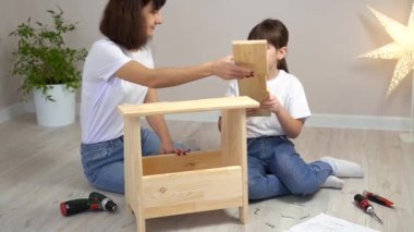 Mutlu aile annesi ve kızı ahşap mobilyaları birleştiriyor. DIY kavramı