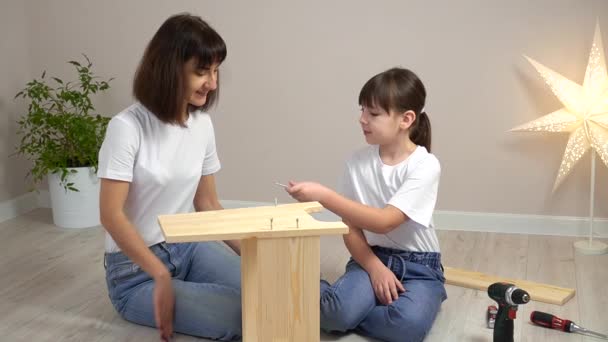 Gelukkige familie moeder en dochter monteren houten meubels samen met schroevendraaier. DIY-concept — Stockvideo