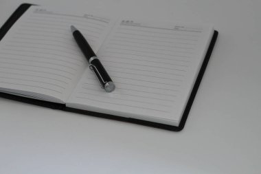 Beyaz arkaplan ile açık günlük üzerine yerleştirilen kalem