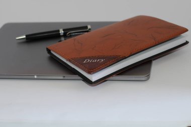 Beyaz arkaplanda kalem ve günlük bulunduran Macbook pro