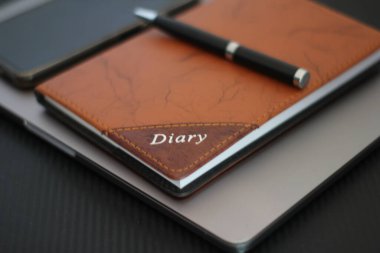 Siyah arka planda kalemi ve günlüğü olan Macbook pro
