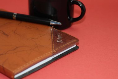 Kırmızı zemin üzerinde siyah bardak ve kalem olan günlük