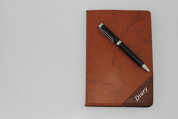 Pen placed on diary with white background