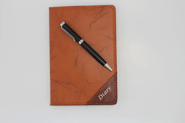 Pen placed on diary with white background