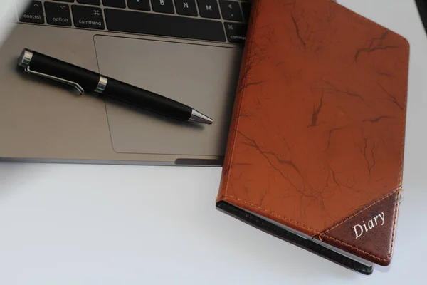 Macbook pro with pen and diary on white background