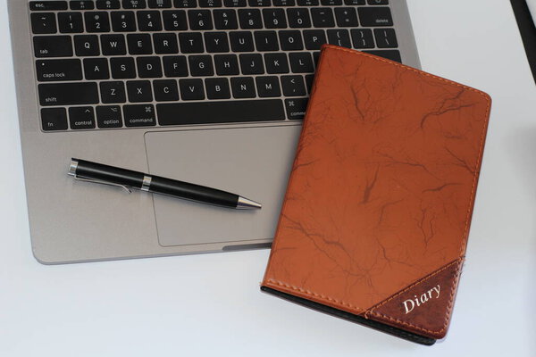 Macbook pro with pen and diary on white background