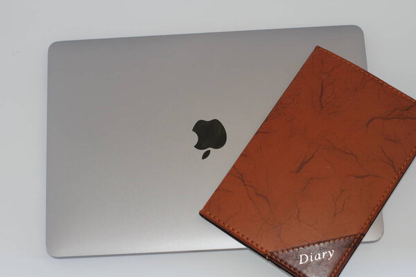Macbook pro with pen and diary on white background