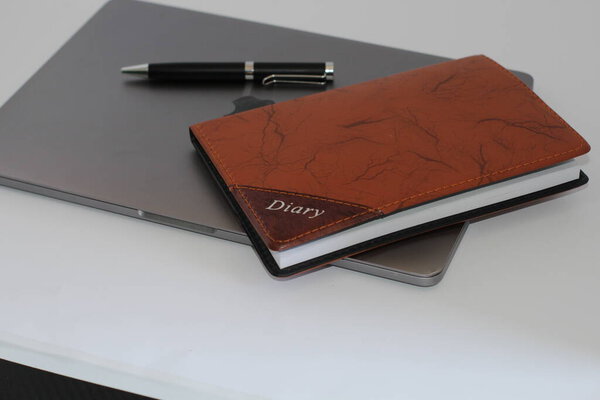 Macbook pro with pen and diary on white background