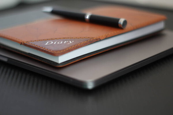 Macbook pro with pen and diary on black background