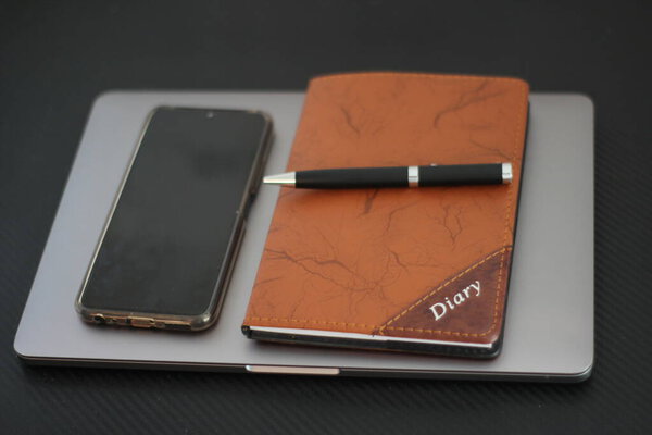 Macbook pro with pen and diary on black background