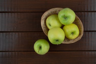 Tahta masadaki sepetteki yeşil elmalar, üst görünüm, kopyalama alanı.
