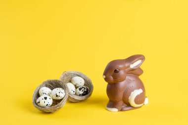 Çikolatalı Paskalya tavşanı ve sarı arka planda yumurtalar. .