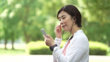 Akıllı telefonuyla müzik dinlerken koşan bir kadın.