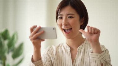 Akıllı telefonunda işaret dili parmak harfleri okuyan bir kadın. 