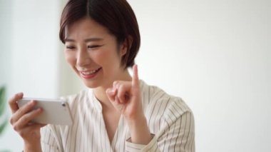 Akıllı telefonunda işaret dili parmak harfleri okuyan bir kadın. 