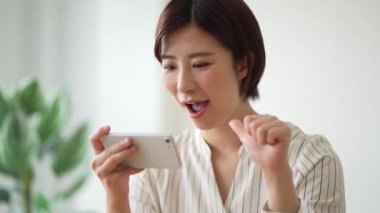 Akıllı telefonunda işaret dili parmak harfleri okuyan bir kadın. 