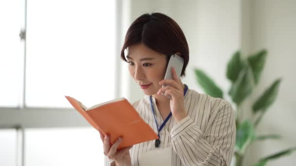 Female Employee Who Opens Notebook While Talking Phone — Stock Video